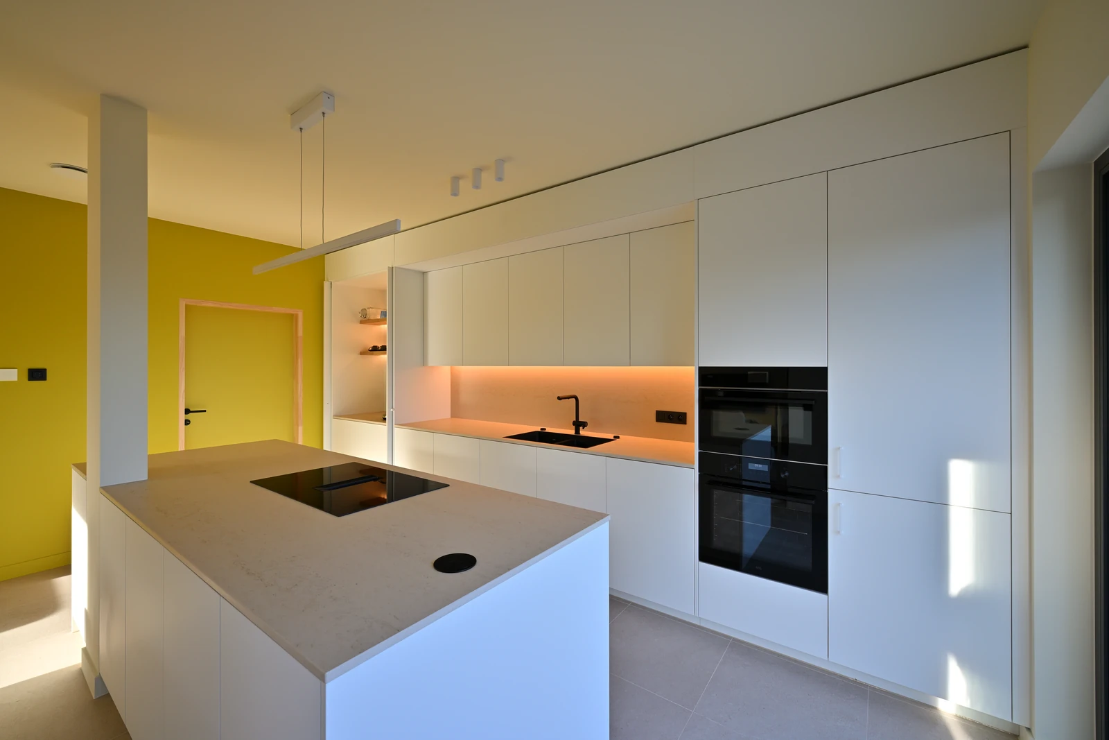 Keuken met kookeiland, kastenwand, toestellen en verlichte nis