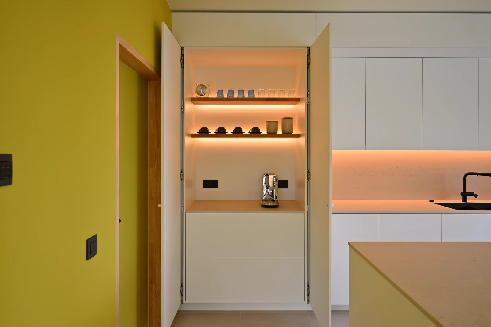 Geopende ontbijtcorner met koffiemachine en verlichte legplanken